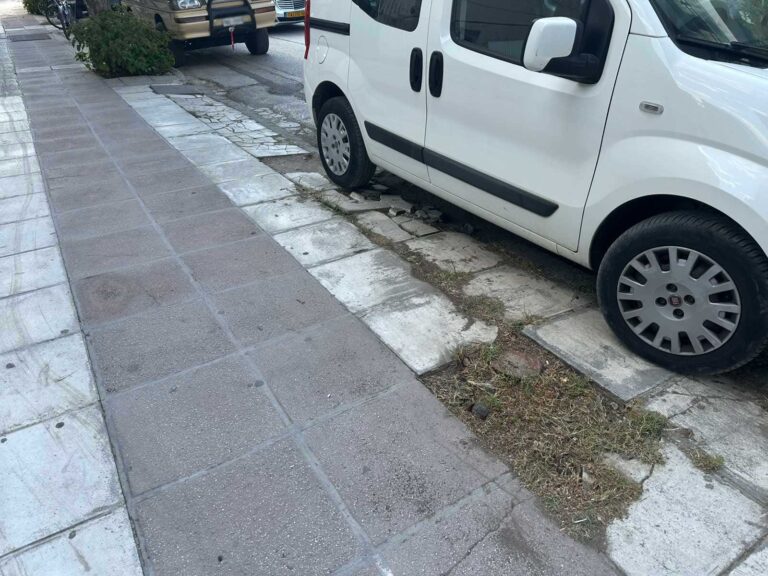 Πεζοδρόμιο με σπασμένες πλάκες και χόρτα στην άκρη δρόμου στα Τρίκαλα