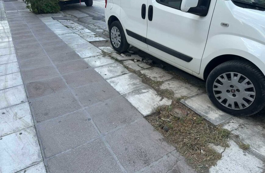 Πεζοδρόμιο με σπασμένες πλάκες και χόρτα στην άκρη δρόμου στα Τρίκαλα