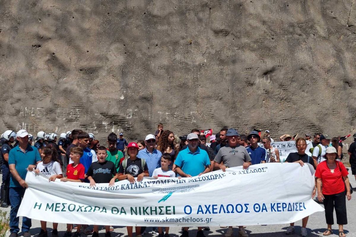Διαδηλωτές στη Μεσοχώρα κρατούν πανό «Η Μεσοχώρα θα νικήσει – Ο Αχελώος θα κερδίσει» στη στέψη του φράγματος.