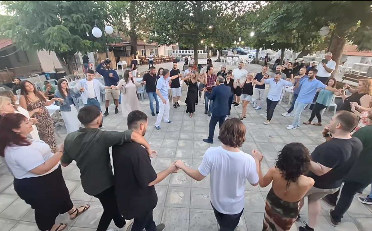 Κάτοικοι και επισκέπτες χορεύουν σε κύκλο στην πλατεία του Λιοπράσου Τρικάλων κατά τη δημοτική βραδιά 2025