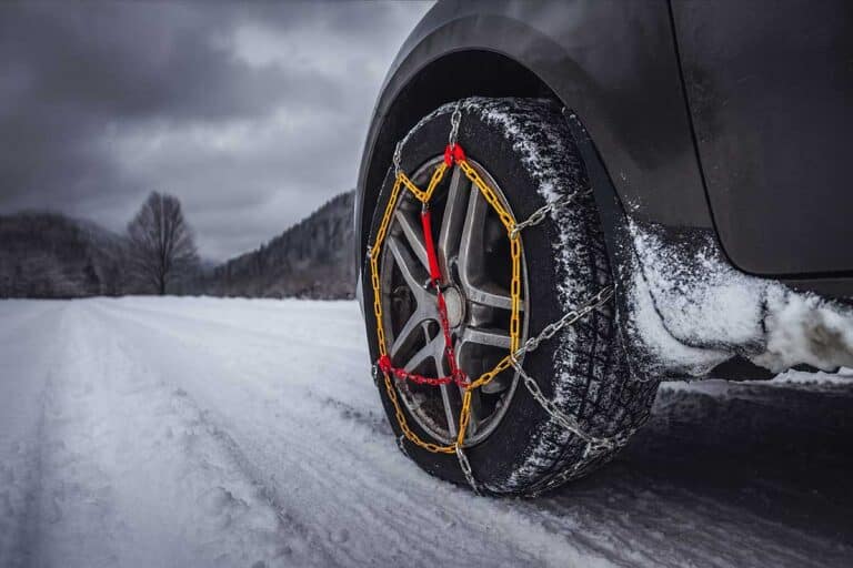 Ρόδα αυτοκινήτου με αντιολισθητικές αλυσίδες σε χιονισμένο δρόμο σε ορεινό τοπίο