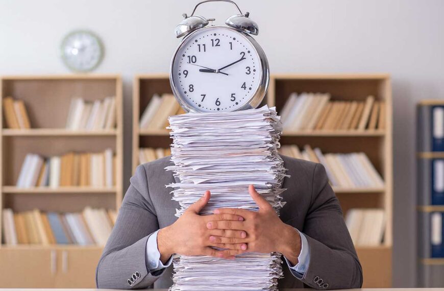Δημόσιος υπάλληλος με στοίβα φακέλων και ρολόι, συμβολική εικόνα για συνταξιοδότηση και γραφειοκρατία