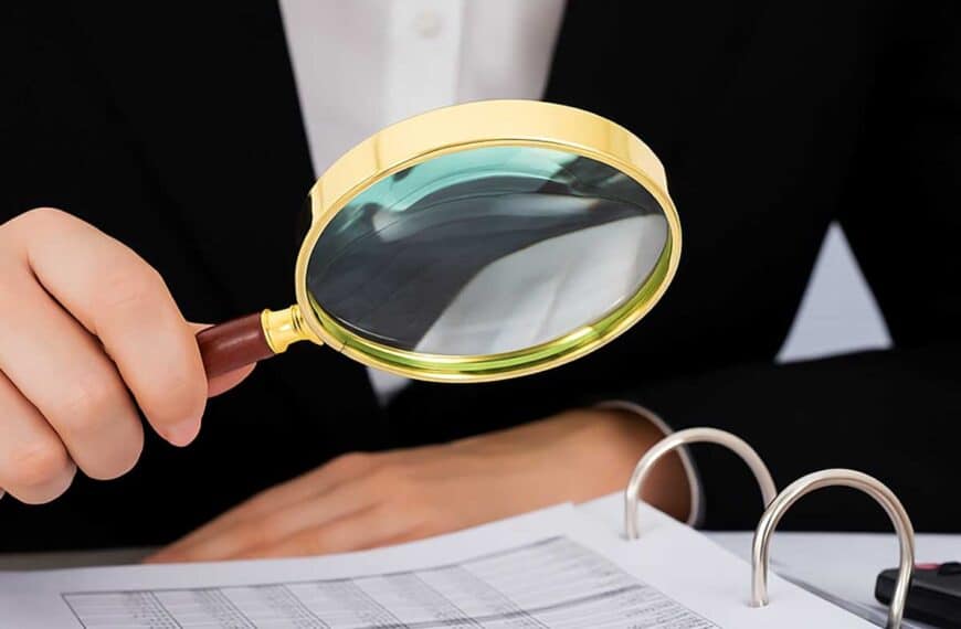 Έλεγχος οικονομικών στοιχείων με μεγεθυντικό φακό και χαρτονομίσματα ευρώ σε γραφείο