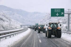 Αγροτικά τρακτέρ αποχωρούν από τον Ε65 σε χιονισμένο τοπίο, μετά το τέλος του μπλόκου των αγροτών