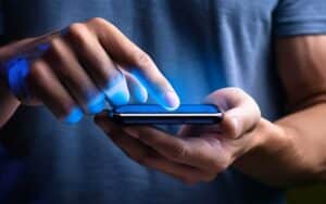 αντρικά χέρια χρησιμοποιούν κινητό τηλέφωνο σε σκοτεινό περιβάλλον