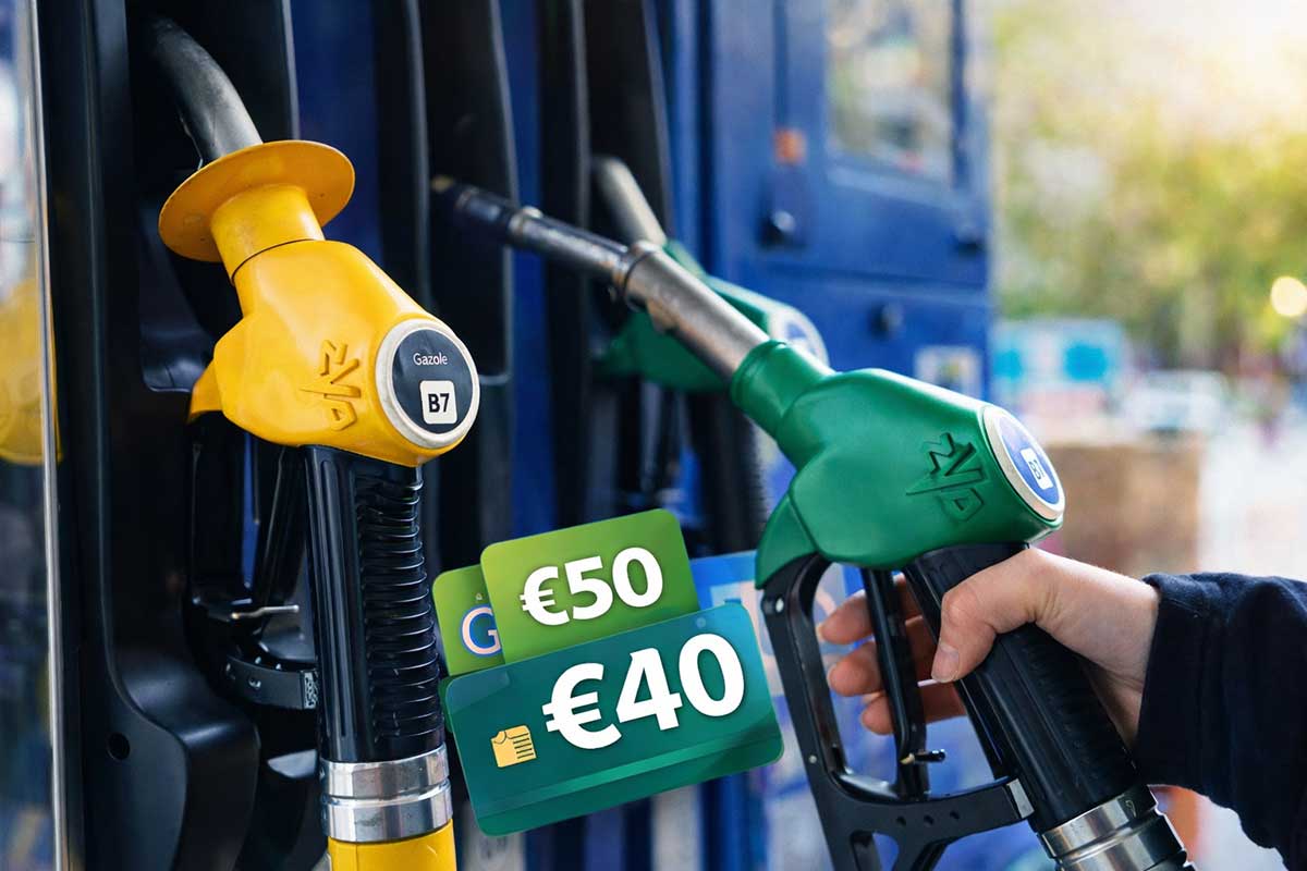 χέρι που κρατά αντλία καυσίμων σε πρατήριο με φόντο άλλες αντλίες και κάρτες επιδότησης καυσίμων